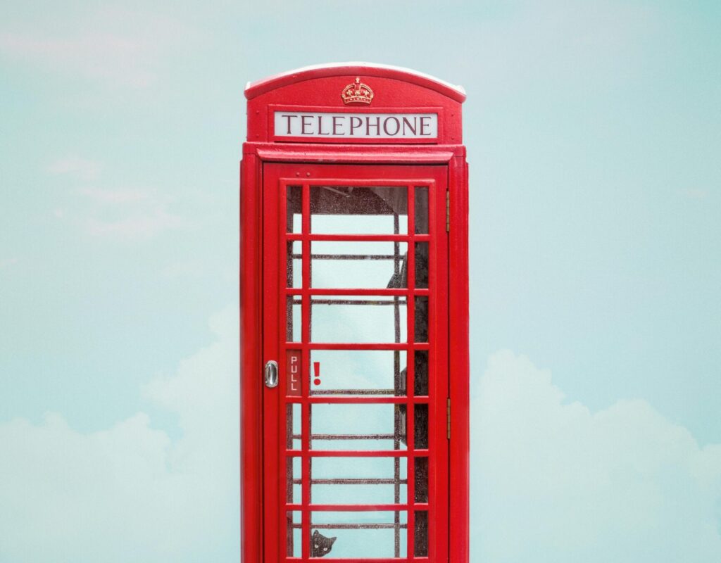 Minimalist photo of a red telephone booth in London with a clear blue sky.